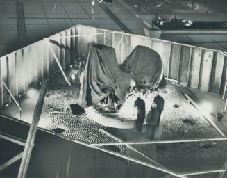 Plywood curtain for 'Archer'. Workmen keep eye on Three Way Piece No. 2-The Archer, but wooden fence keeps public's eye off it until it is unveiled to(...)