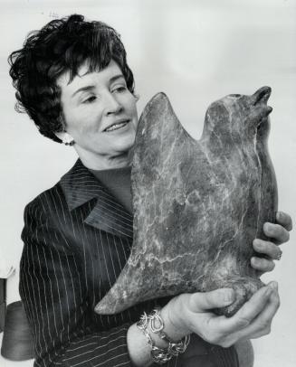 Every piece an original. Mrs. Howard Fogarty, shop supervisor of the Canadian Guild of Crafts, holds sculpture of owl created by Eskimo sculpture Ezee(...)