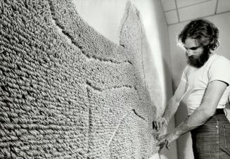 Artist combs out his work. Artist David Kaye combs Linen 1977, one of hangings in his exhibition of weaving that is being shown at the Glendon College(...)
