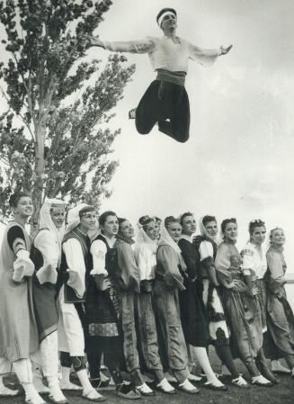 Leapin' lizards - what a dance! Nikola Bojich leaps over th heads of 12 women dressed in costumes represting different regions of Yugoslavia. The danc(...)