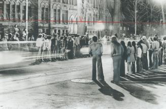 Light streaks in time exposure are from cars drag-racing on street in front of Frederiction's courthouse, as crowds line route. Cars ran red lights
