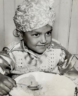 The Turban of their homeland is still in use, and this young fellow wears one as he sits at table during festivities in the famous Sikh temple in Vancouver