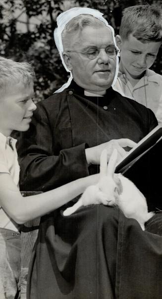 Father Palmer, Cowley Father Superior, is showing an illustrated history book to two boys who get their schooling at this Bracebridge mission. One of (...)