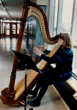 Julia Seager plays her harp in the school corridors of the Etobicoke School of the Arts