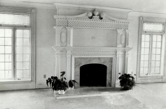 An imposing fireplace with windows on each side is hand carved
