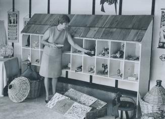 Mrs. Reading saved chicken rests to use as goods stands, Mrs. S. McDonough of the Toronto Wimodausis club overlooks some gift items