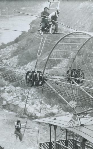 Winding up his daredevil trip above the Niagara Gorge whirlpool today, French acrobat Henri Rechatin steps down onto the aerial car cable from a motor(...)