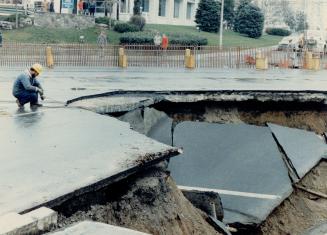 Image shows a worker inspecting a pothole.