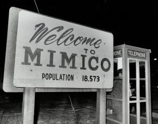 White sign affixed to two wooden posts displays the text, Welcome to Mimico - population 18,573 ...