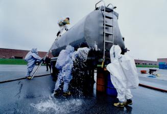 Mississauga firefighters, clad in chemical-resistant suits, clamber aboard a tanker trunk during a training session designed to simulate a toxic mater(...)