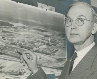 William A. Wecker, General Motors of Canada president, points to an aerial photo of the new Oshawa plant which will step up production to 1,350 vehicles a day