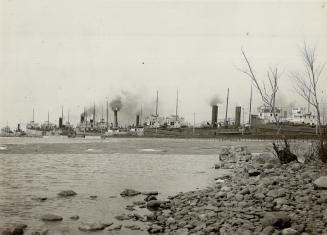 Taken from the shore, this picture shows a number of industrial buildings with many smokestacks ...