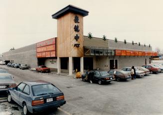 A mall with a wooden tower, bearing Chinese script, and surrounded by cars.