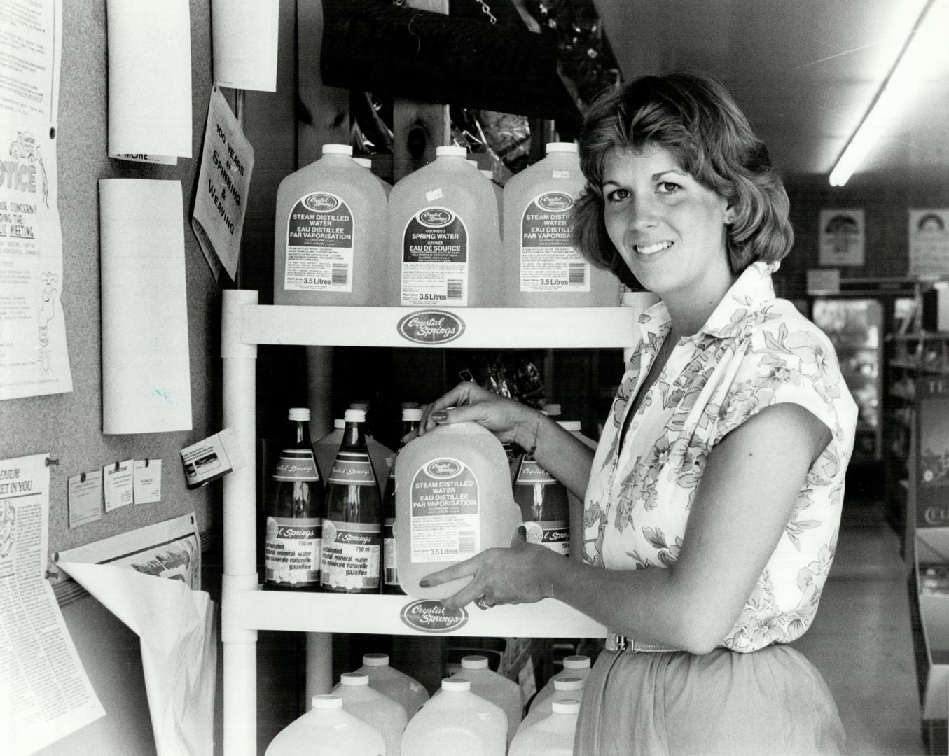 Trudy Wideman manager of health food store holding bottle of distilled water