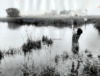 A young angler stands at edge of Oshawa's Second Marsh and casts his line into the water, hoping for a catch