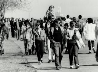 Crowds stroll the Beaches' boardwalk yesterday while Roy Beattie and Lilo Ohm savor city hall's last skating