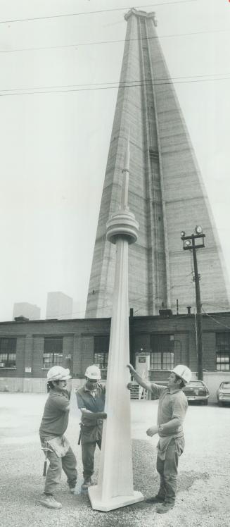 Workmen set up a model of the CN tower