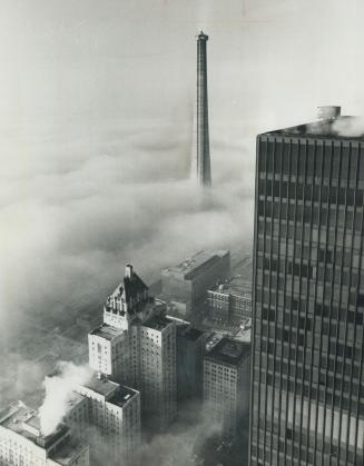 The CN tower, seen from the top of Commerce Court, looms over the fog