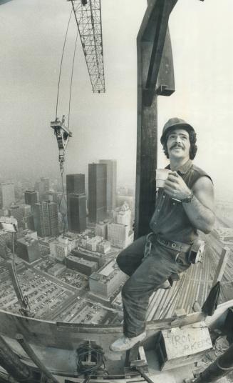 Workman Yvon Rainville, atop the CN tower, lifts his coffee cup in salute to his fellow workers as their towers reaches 785 feet, making it one foot t(...)