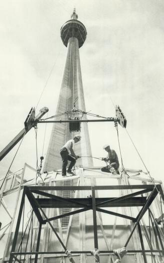 Ironworkers from Skyhook are preparing to hoist a weathershield to the antenna of the tower