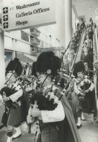 Pipers parade in dignitaries down esclators watched by hundreds in Galleria balconies