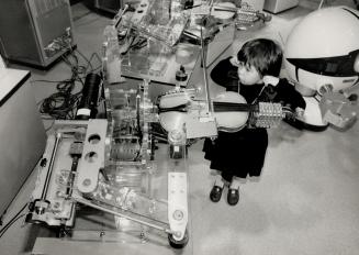 Play it again, Robot. Mariko Macksey, 4, listens as a robot plays violin at the Ontario Science Centre. Five Taito Corp. machines, expert at violin, f(...)