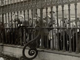 Some of the crowd of curious persons Which gathered outside the iron fence of Osgoode Hall to see the various personalities, gazing through the iron rails