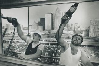New neighbor on the waterfront, Against a backdrop of downtown Toronto's skyline, Gino Dallaire, left, and Daniel Smith install metal window frames in(...)