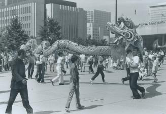 A Dragon Dance in Nathan Phillips Square. Many people look on.