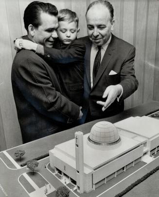 New Greek Church on the Way, Peter Roniotis, holding son, and Peter palmer, president of the Greek community of Metro, look at a model of Greek Orthod(...)