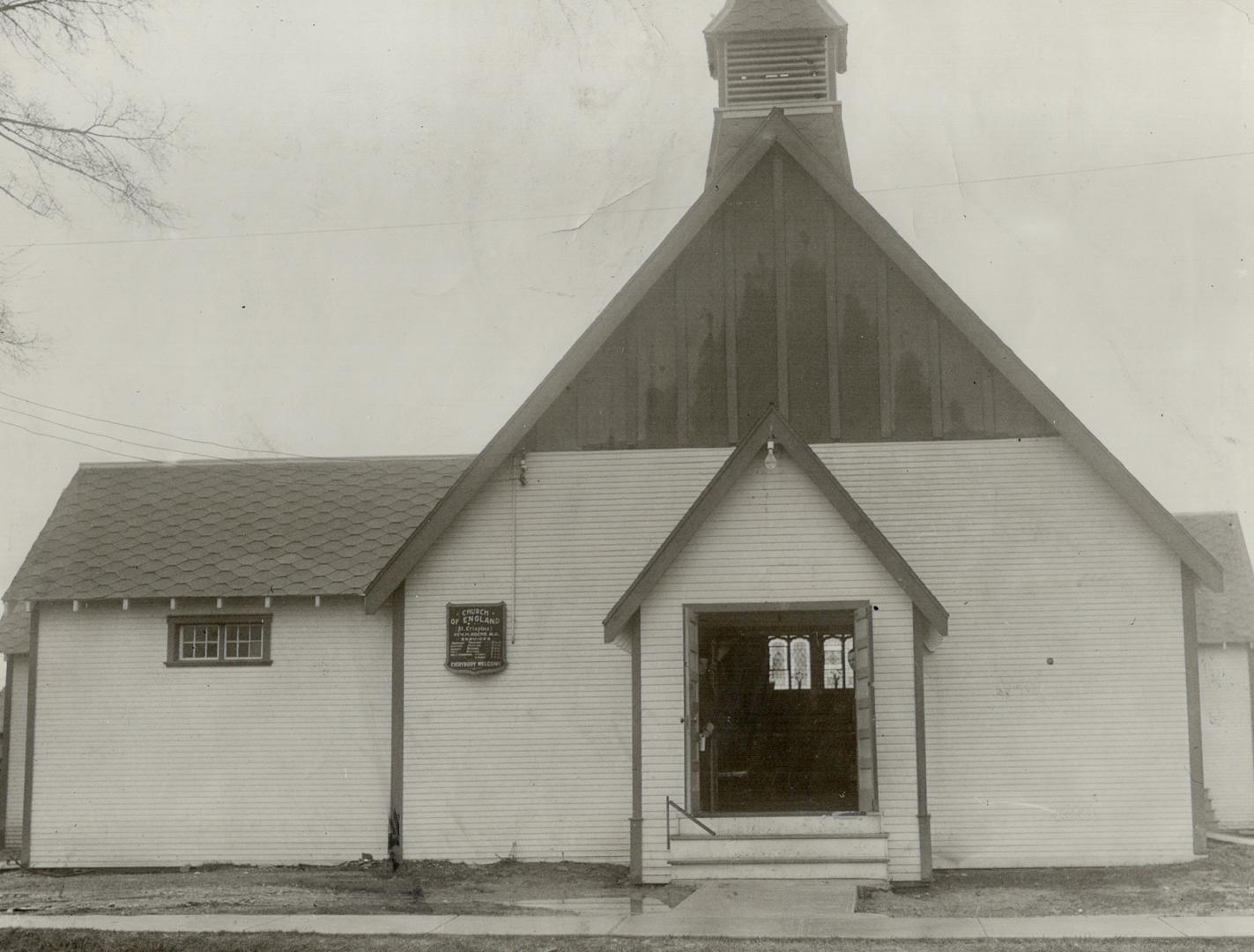 Exterior of church with white siding, honeycomb tile on left roof and small belfry tower above  ...