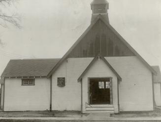 Exterior of church with white siding, honeycomb tile on left roof and small belfry tower above  ...
