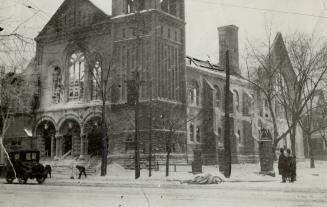 Snowy view of brick church seen from intersection. Front of church features lancet windows abov ...