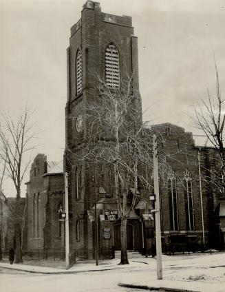 Exterior of brick church with elongated arched windows and prominent belfry tower. Sign hanging ...