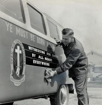 Norman Wyman polishes up his evangelical van, He's wearing trim blue uniform of the Open Air Crusaders