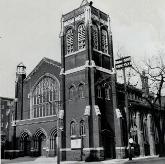 Exterior view of brick church with Belfry tower and prominent arched window above entrance.