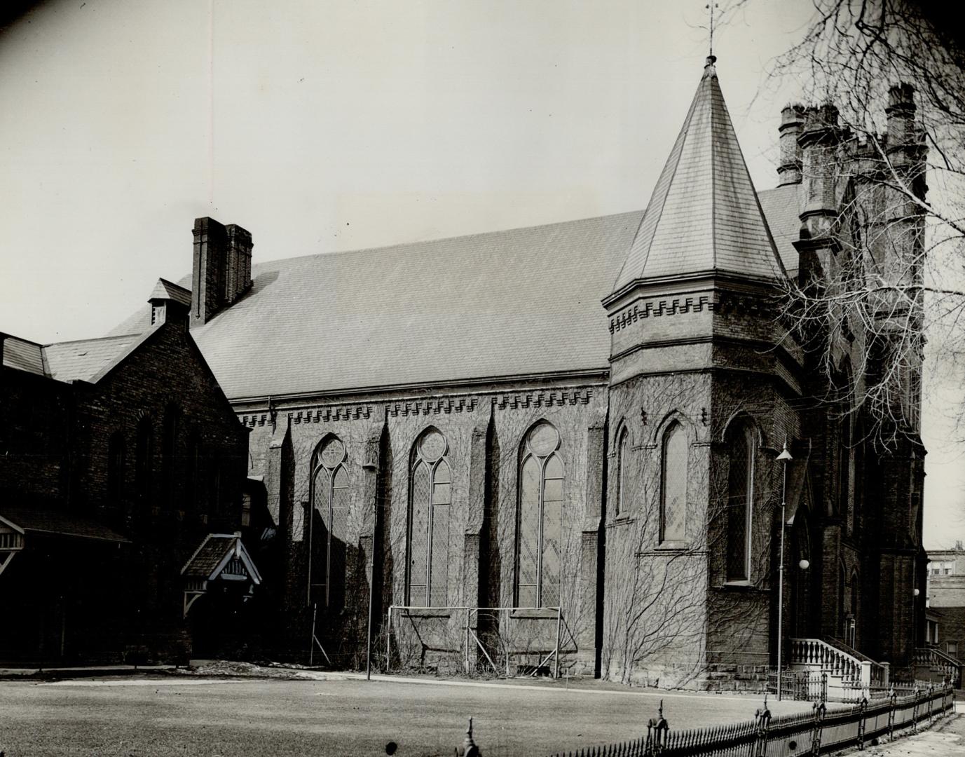 Side view of exterior of church showing arched windows, steeply pitched roof and attached tower ...
