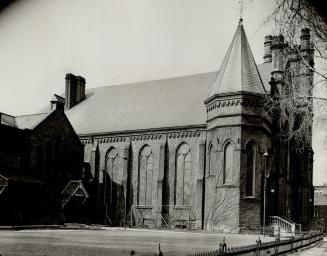 Side view of exterior of church showing arched windows, steeply pitched roof and attached tower…