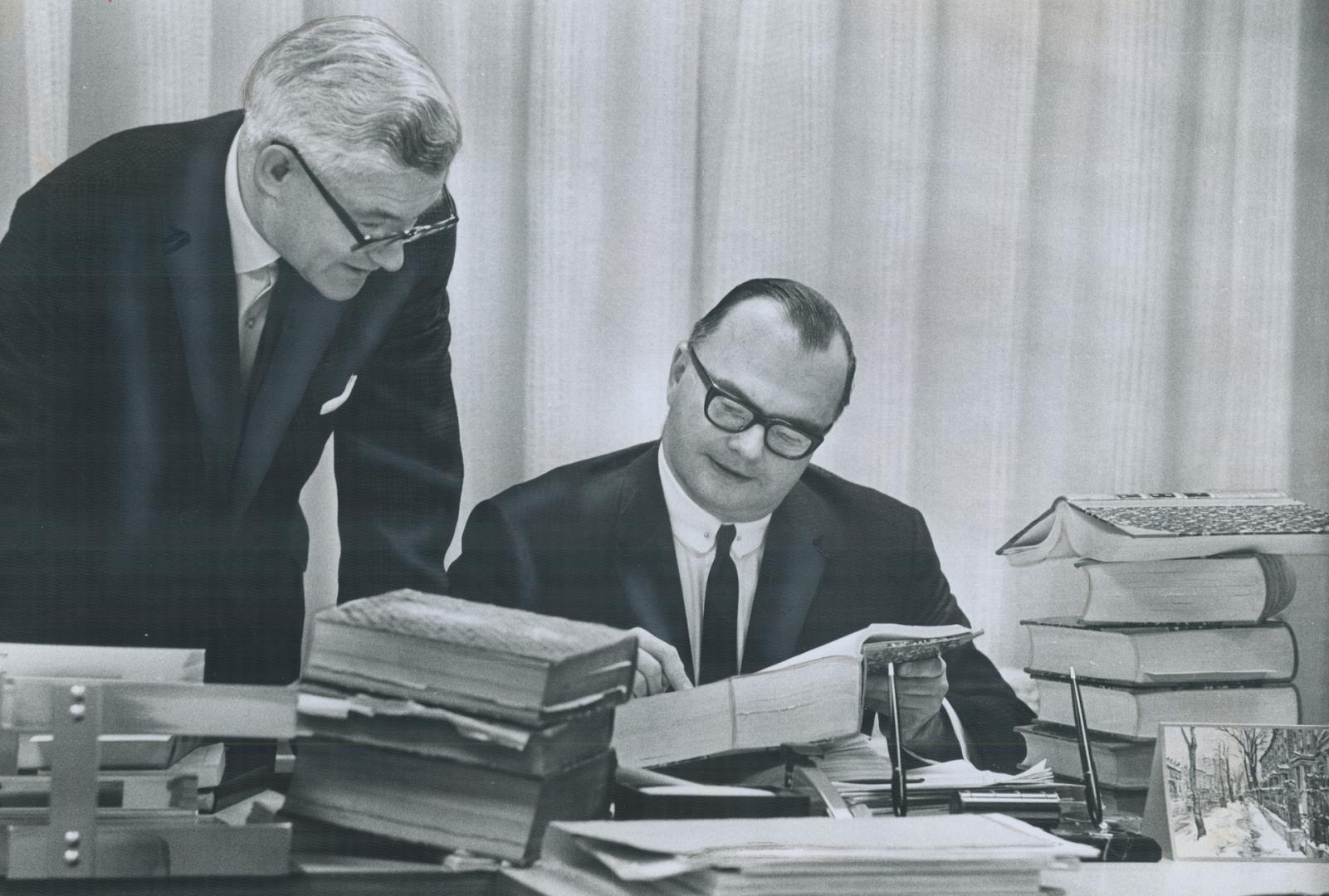 City Solicitor W. J. Callow (Right), Lawyer James McCubbin poring over some of Metro's 80,000 Bylaws, It's estimated the bylaws will have to be studie(...)