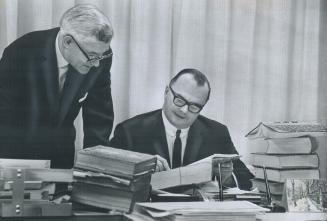 City Solicitor W. J. Callow (Right), Lawyer James McCubbin poring over some of Metro's 80,000 Bylaws, It's estimated the bylaws will have to be studie(...)