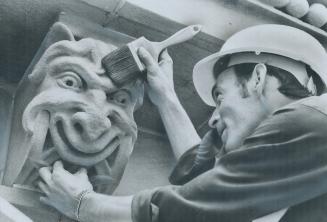 A Grinning Gargoyle directly under the cornice of the old city hall gets a gentle brushing from Leo Cleutt, site foreman for sandblasting of the build(...)