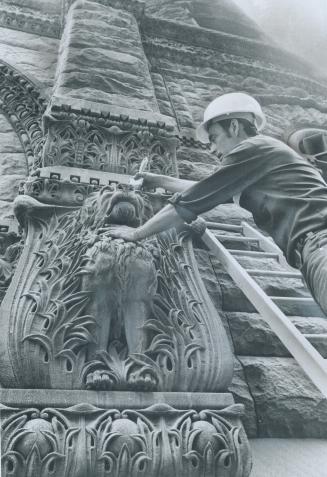 Near the Queen St. entrance to old city hall, foreman Leo Cleutt brushes accumulated sand out of a gargoyle