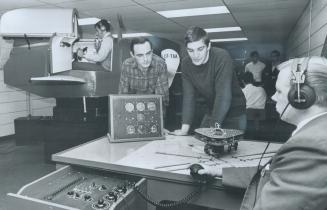 Flying High without even getting off the ground, Marvin Davidovich handles controls of a Link Trainer while fellow Seneca College students Jim McMcoig(...)