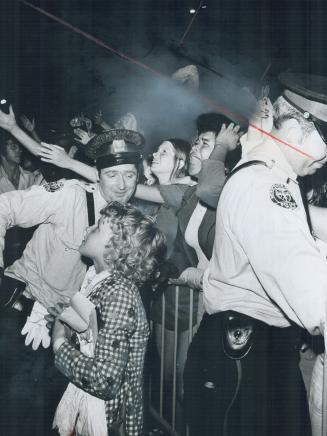 Screaming like love-struck harpies, young fans of the Osmond Brothers are held in check by a policeman