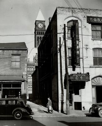 The city hall clock shows behind the Chung King Chop Suey House, near the Chinese Daily Times