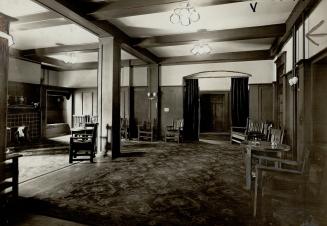 A dark paneled room with tables and chairs lining the perimeter. 