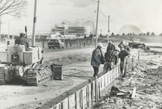 Workmen prepare support bed for magnetic levitation train test track being built at the CNE
