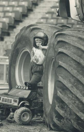 Paul Birmingham, 4, leans casually against one of the monster tires of his uncle's over-sized Chevy
