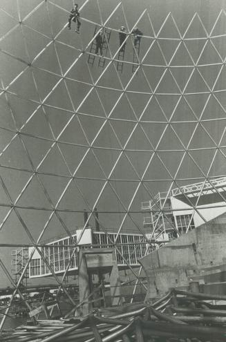 Weaving a cobweb dome at Ontario place, Workmen hang high in the lattice work of geodesic aluminum dome they are building to roof the theatre at Ontario Place on Toronto's waterfront