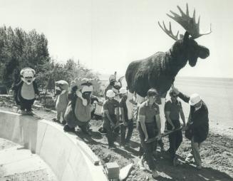The animals meet the animals, Quesar the moose arrives at Ontario Place yesterday as workers take it to its grazing site at a wilderness lake. And a merry group of costumed characters follow
